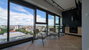 a kitchen with a table and chairs and large windows at Apartament Loft Olszynki Park in Rzeszów