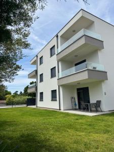 a white building with a lawn in front of it at Apartments Frank in Zambratija