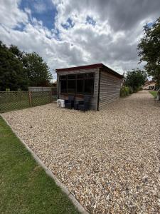 a small building on a gravel yard with a house at Summerhouse in Honington