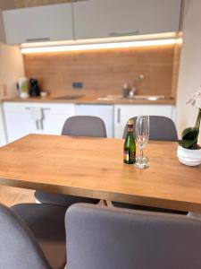 a bottle of wine and glasses on a wooden table at Adriany apartmán in Bayerisch Eisenstein