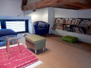 a living room with a chair and a table and a book shelf at Le Petit Vigneau in Ménil