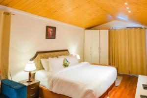 a bedroom with a white bed and a wooden ceiling at Holiday In Homestay in Shimla