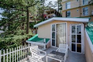 a tiny house with two chairs and a porch at Holiday In Homestay in Shimla