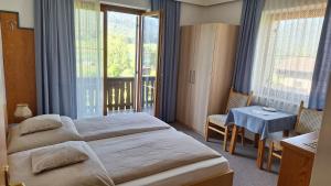 a hotel room with a bed and a table and windows at Haus Alpenfriede in Weissensee
