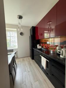 a kitchen with black counters and red cabinets at Lielais prospekts 54 in Ventspils
