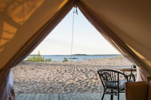 a tent on a beach with a table and a chair at Gnista Glamping in Fäboda