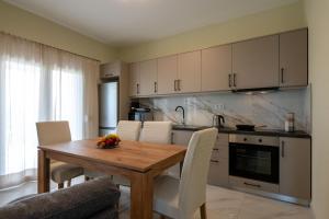 a kitchen with a wooden table and white chairs at Anima Horizon - Thea apartment in Elaiófiton