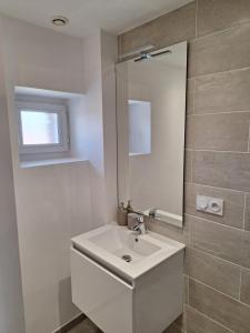 a bathroom with a white sink and a mirror at La Campanule in Saint-Cyr-en-Pail