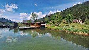 a lake with a house and a dock next to a mountain at Haus Alpenfriede in Weissensee