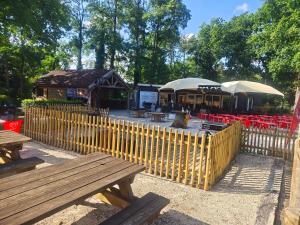 a wooden fence with benches and tables in a park at Les mobil homes d’oliver rob in Saint-Chéron