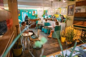 a group of people sitting at tables in a restaurant at Nativus Art Hostel in San José