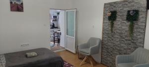 a room with a bed and two chairs and a brick wall at Ánizs Apartmanház in Makó