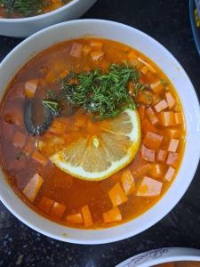 a bowl of soup with a lemon slice in it at GuestHouse "ERKIN" in Karakol