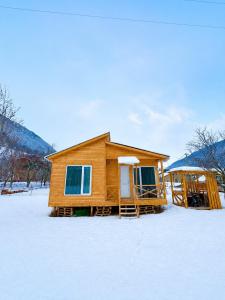 a log cabin in the snow with snow covered ground at HOMELAND in Mestia