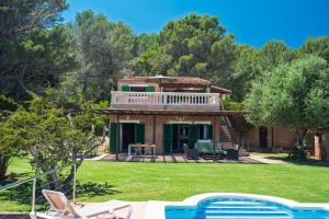 a house with a balcony and a yard with chairs at Maricel in Cala Ratjada