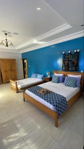 a bedroom with two beds and a blue wall at B & B Villa Calliandra in Bijilo +43 photos