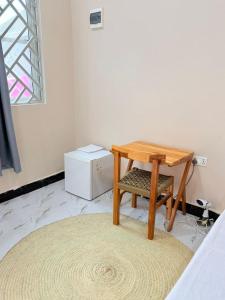 a small wooden table and a stool in a room at Rocky Apartment Zanzibar in Zanzibar City