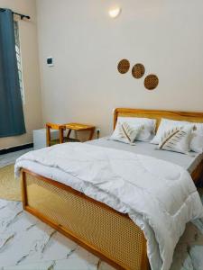 a bed with white sheets and pillows in a room at Rocky Apartment Zanzibar in Zanzibar City