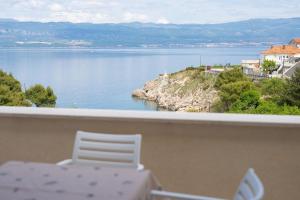 a table and chair on a balcony with a view of the water at Apartman Pina in Vrbnik
