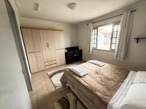 a bedroom with a bed and a window and a desk at Morada Pé de Laranja in Lages