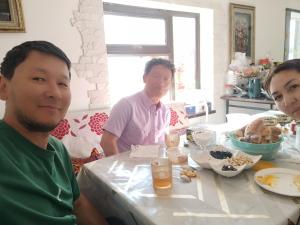 a group of people sitting at a table with food at Алима in Ottuk