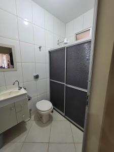 a bathroom with a shower with a toilet and a sink at Suíte independente com cozinha e varanda in Piúma