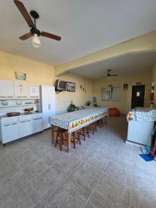 a room with a table and a kitchen with a ceiling fan at Suíte independente com cozinha e varanda in Piúma