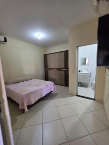 a bedroom with a pink bed and a bathroom at Suíte independente com cozinha e varanda in Piúma