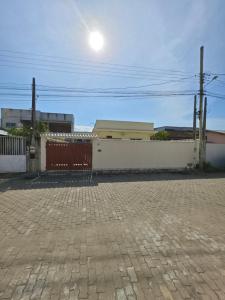 a white building with a red fence and a street light at Suíte independente com cozinha e varanda in Piúma
