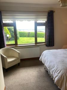 a bedroom with a bed and a chair and a window at Islandview House in Clonbur