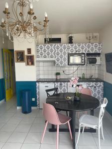 a kitchen with a black table and pink chairs at Bulle d amour in Granville +21 photos
