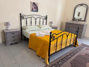 a bedroom with a bed with a yellow blanket and two night stands at House S&D in Giarre