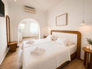 a bedroom with a large white bed with two towels on it at Eleftheria Hotel & Apartments in Ornos