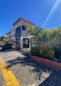 a building on a street with palm trees and plants at Hospede-se com conforto em Capim Macio in Natal