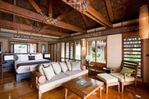 a bedroom with a bed and a couch and a table at Likuliku Lagoon Resort - Adults Only in Malolo