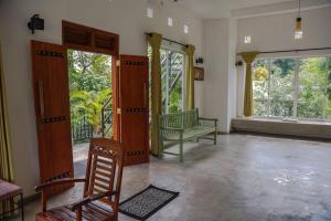 a living room with two chairs and a bench and windows at Everdew Kandy in Kandy