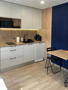 a kitchen with white cabinets and a table and a table and chairs at Calm Village in Zator