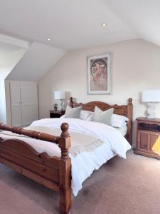 a bedroom with a large wooden bed with white sheets at Broadlands View in Shaldon