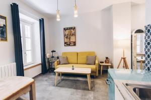 a living room with a yellow couch and a table at Casa Caracol in Cádiz