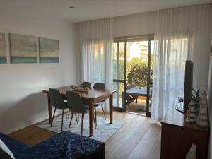 a dining room with a table and chairs and a television at My Little Beach House in Praia da Barra