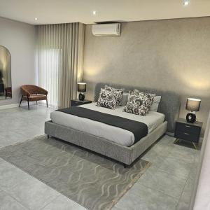 a bedroom with a large bed and a chair at Mupauli Boutique Lodge in Hartbeesbult