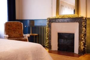 a room with a fireplace with a chair and a mirror at L' Accointance in Semur-en-Auxois