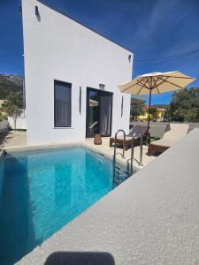 a villa with a swimming pool and an umbrella at Sage Villas in Plataria