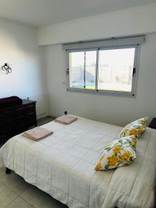 a white bedroom with a large bed with two pillows at Los Agapanthus in General Belgrano