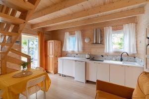 a kitchen with white cabinets and a table in a room at Domki Błękitne Nad Morzem Międzywodzie in Międzywodzie