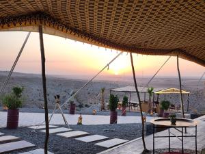 a view of the desert from under a straw umbrella at Travel sky morocco camp in El Karia