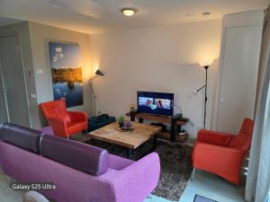 a living room with a purple couch and red chairs at Onderlandhuis 38 in Chaam