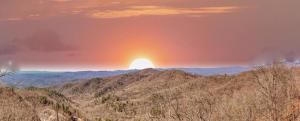 a sunset over a mountain range with the sun in the background at Calling Me Home in Lenoir