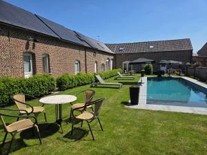 a backyard with a table and chairs and a pool at B&B Het Doctershoes in Kinrooi