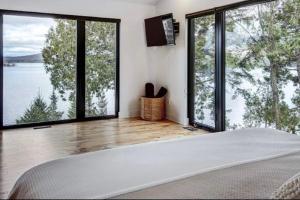 a bedroom with large glass windows and a large bed at Chalet ouareau in Saint-Donat-de-Montcalm